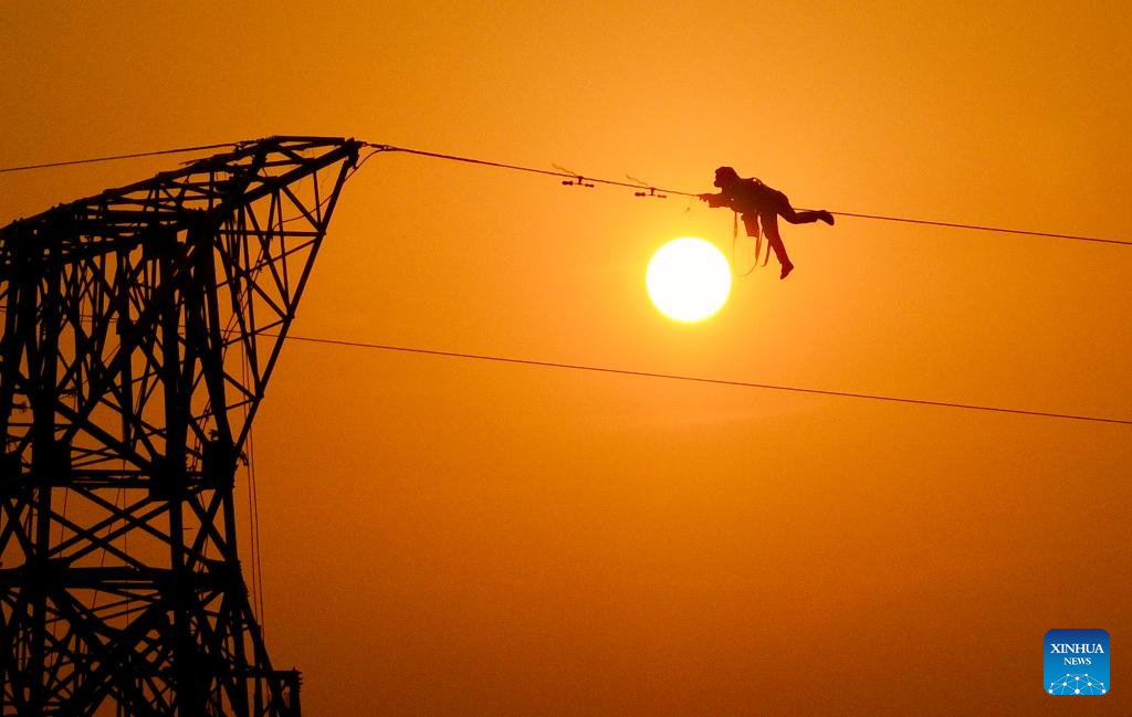 A drone photo taken on Dec. 16, 2025 shows constructors working on a power transmission line in east China's Anhui Province. The main-body construction of the 500-kV power transmission line from Xiangjian to Ludao in Anhui Province was successfully completed on Wednesday. With a total length of 136.8 kilometers, the line will further optimize the power grid structure of Anhui and enhance power supply reliability upon completion. (Photo by Zheng Xianlie/Xinhua)