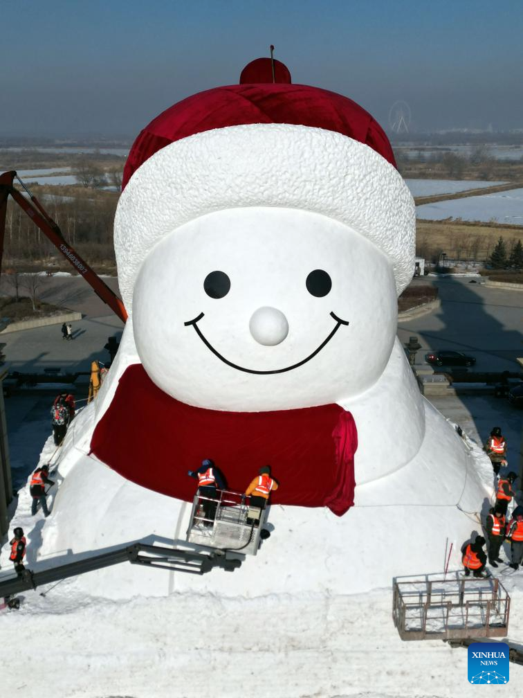 A drone photo shows workers building a giant snowman at the Qunli music park in Harbin, northeast China's Heilongjiang Province, Dec. 14, 2025. This year's giant snowman, 19 meters in height and made with some 3,000 cubic meters of snow, is one meter taller than that of last year. (Photo by Liu Yang/Xinhua)