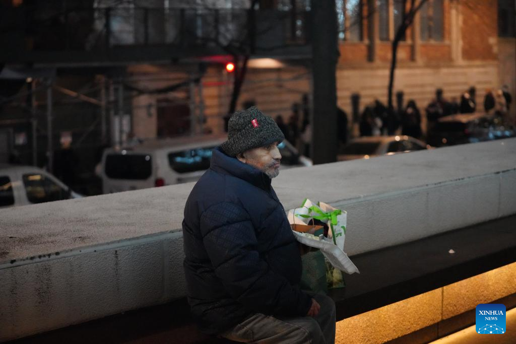 A man eats free food received from a shelter in New York City, the United States, Dec. 17, 2025. (Xinhua/Zhang Fengguo)
