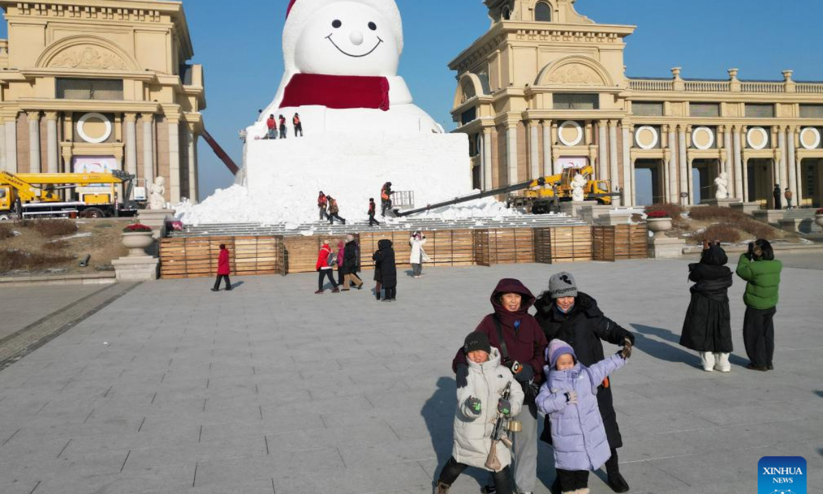 A drone photo shows workers building a giant snowman at the Qunli music park in Harbin, northeast China's Heilongjiang Province, Dec. 14, 2025. This year's giant snowman, 19 meters in height and made with some 3,000 cubic meters of snow, is one meter taller than that of last year. (Photo by Liu Yang/Xinhua)