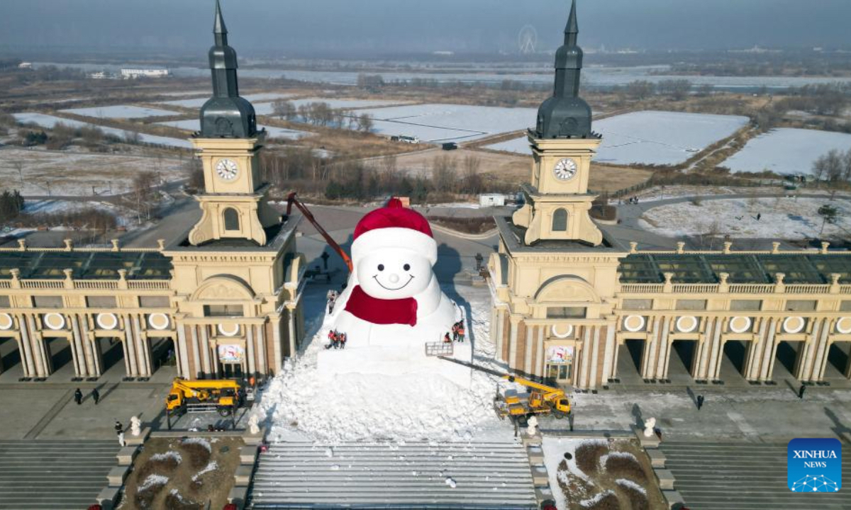 A drone photo shows workers building a giant snowman at the Qunli music park in Harbin, northeast China's Heilongjiang Province, Dec. 14, 2025. This year's giant snowman, 19 meters in height and made with some 3,000 cubic meters of snow, is one meter taller than that of last year. (Photo by Liu Yang/Xinhua)