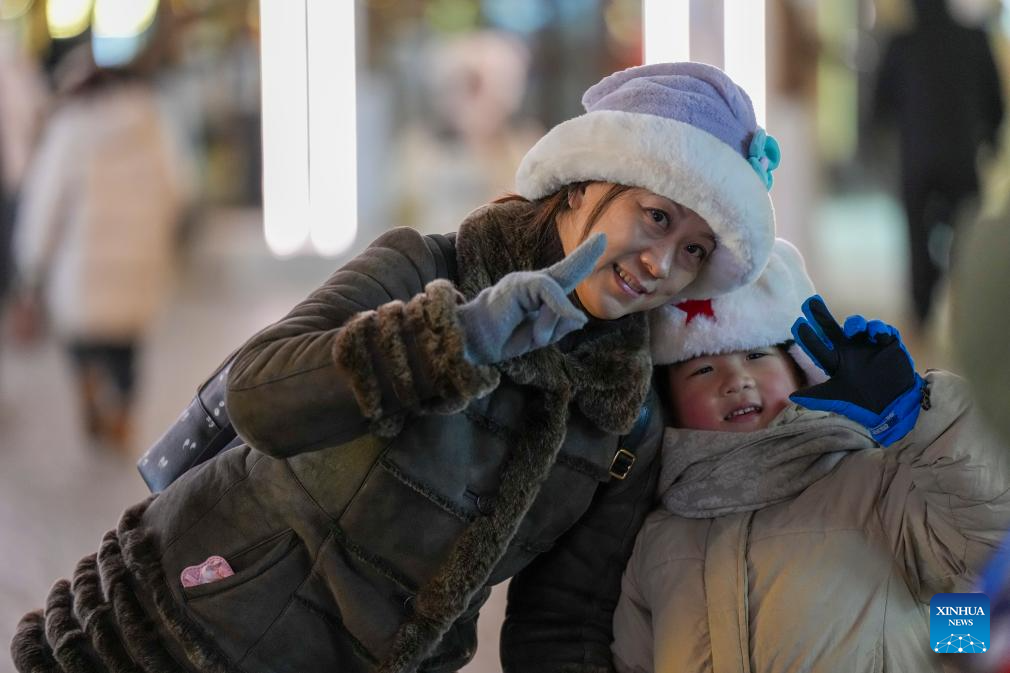 Tourists pose for photos on the Central Street in Harbin, capital of northeast China's Heilongjiang Province, Dec. 16, 2025. As one of the most popular attractions in Harbin, the Central Street, which is renowned for its diverse European-style architecture, wows tourists with its ice and snow sculptures and folk shows during the city's tourism boom this winter. (Xinhua/Wang Song)