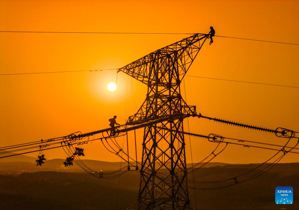 A drone photo taken on Dec. 16, 2025 shows constructors working on a power transmission line in east China's Anhui Province. The main-body construction of the 500-kV power transmission line from Xiangjian to Ludao in Anhui Province was successfully completed on Wednesday. With a total length of 136.8 kilometers, the line will further optimize the power grid structure of Anhui and enhance power supply reliability upon completion. (Photo by Zheng Xianlie/Xinhua)