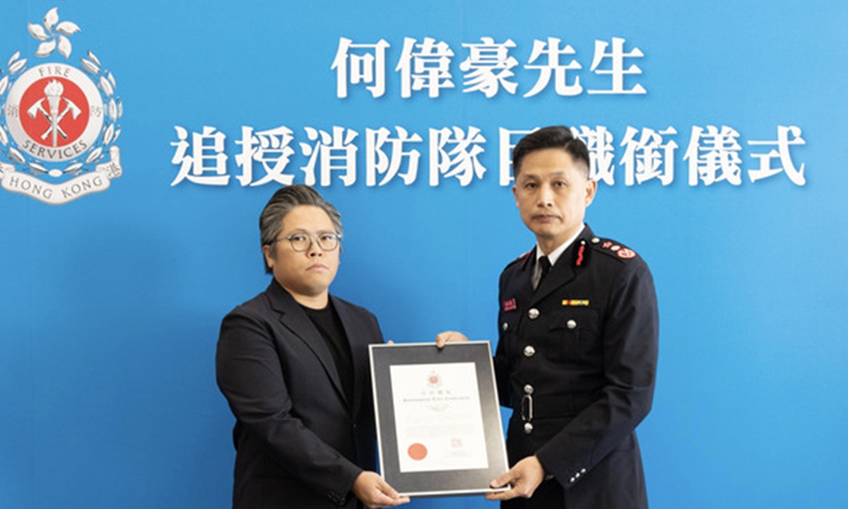 A family member of deceased fireman Ho Wai-ho accepts, on his behalf, a posthumous title conferment certificate from Director of Fire Services Andy Yeung (right) of the Hong Kong Special Administrative Region (HKSAR). Photo: HKSAR government's website.