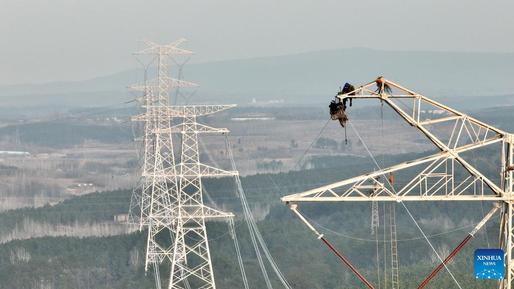 A drone photo taken on Dec. 16, 2025 shows constructors working on a power transmission line in east China's Anhui Province. The main-body construction of the 500-kV power transmission line from Xiangjian to Ludao in Anhui Province was successfully completed on Wednesday. With a total length of 136.8 kilometers, the line will further optimize the power grid structure of Anhui and enhance power supply reliability upon completion. (Xinhua/Zhou Mu)