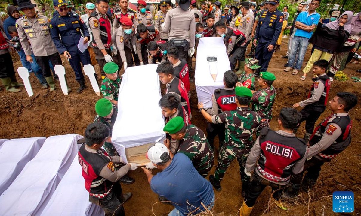 Police officers lay coffins during a mass burial for victims of floods and landslides in Agam regency, West Sumatra, Indonesia, Dec. 11, 2025. The death toll from floods and landslides that struck three provinces on Indonesia's Sumatra Island has exceeded 1,000, with 218 people still missing, according to the latest data released Saturday by the National Disaster Management Agency (BNPB). (Photo by Andri Mardiansyah/Xinhua)