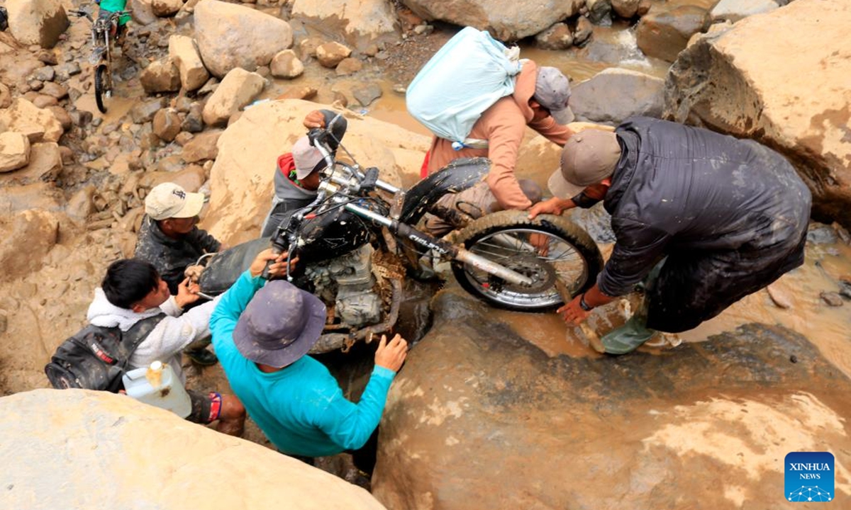 Villagers move a motorcycle across a river after floods and landslides hit Bener Meriah regency in Aceh, Indonesia, Dec. 9, 2025. The death toll from floods and landslides that struck three provinces on Indonesia's Sumatra Island has exceeded 1,000, with 218 people still missing, according to the latest data released Saturday by the National Disaster Management Agency (BNPB). (Photo by Yulham/Xinhua)