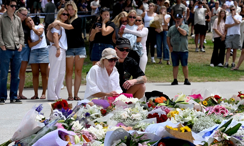 Mourners gather by floral tributes at the Bondi Pavillion in memory of the victims of a shooting at Bondi Beach, in Sydney on December 15, 2025.