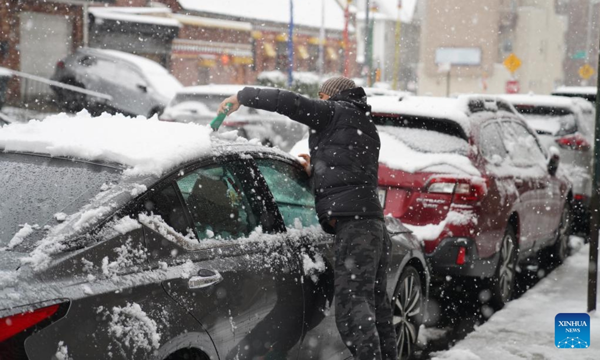 A man clears snow on a vehicle on a street in New York, the United States, on Dec. 14, 2025. (Xinhua/Zhang Fengguo)