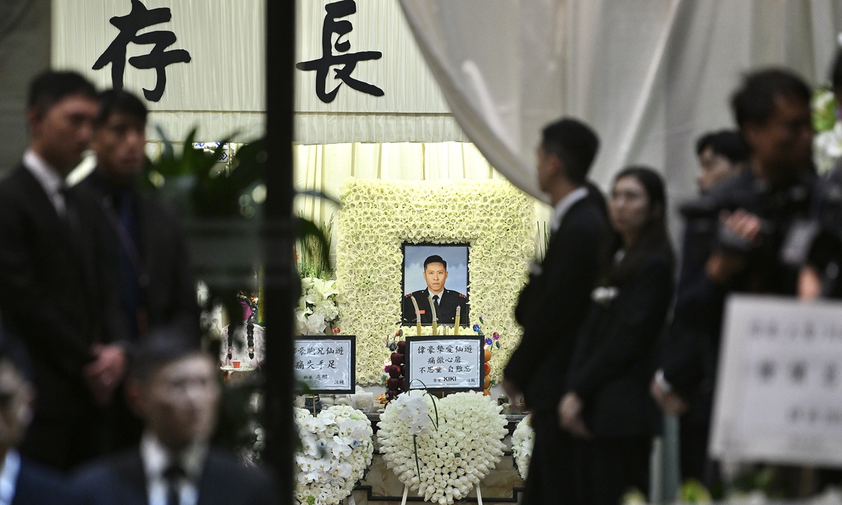On December 18, 2025, officials attend a memorial service in Hung Hom, Hong Kong, for firefighter Ho Wai-ho, who gave his life to fight the deadly fire at Wang Fuk Court in Tai Po. HKSAR Chief Executive John Lee attended to pay his respects, while numerous floral tributes from all sectors of society adorned the exterior of the funeral home in memory of Ho. Photo: VCG