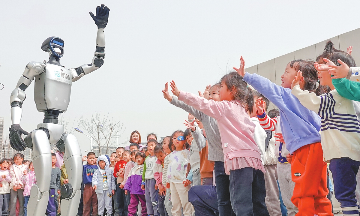 A humanoid robot waves to children at a kindergarten in the Yantai High-tech Zone, East China's Shandong Province, on March 24, 2025. Photo: VCG