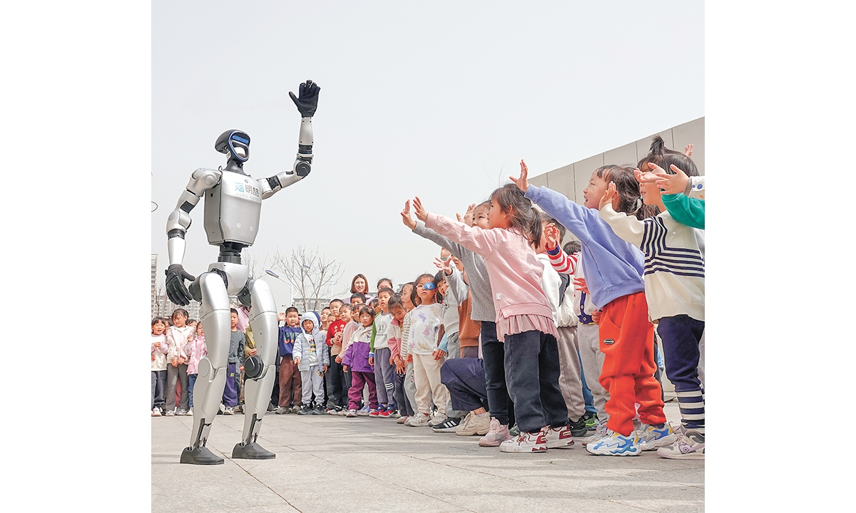 A humanoid robot waves to children at a kindergarten in the Yantai High-tech Zone, East China's Shandong Province, on March 24, 2025. Photo: VCG