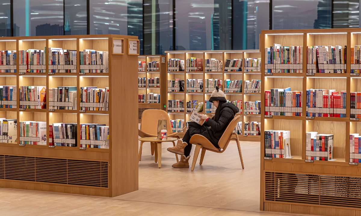 A woman reads a book in a library in Beijing. Photo: VCG