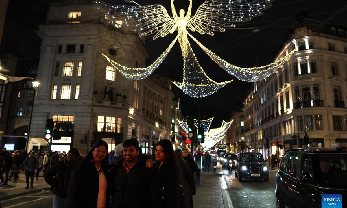 People pose for photos on Regent Street decorated with lights in London, Britain, on Dec. 17, 2025. (Xinhua/Li Ying)