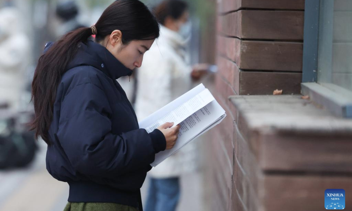 An examinee reviews her study materials before entering an examination site for the 2026 postgraduate entrance exam in Shijiazhuang, north China's Hebei Province, Dec. 20, 2025. China's national exam for postgraduate enrolment kicked off on Saturday. (Photo by Liang Zidong/Xinhua)
