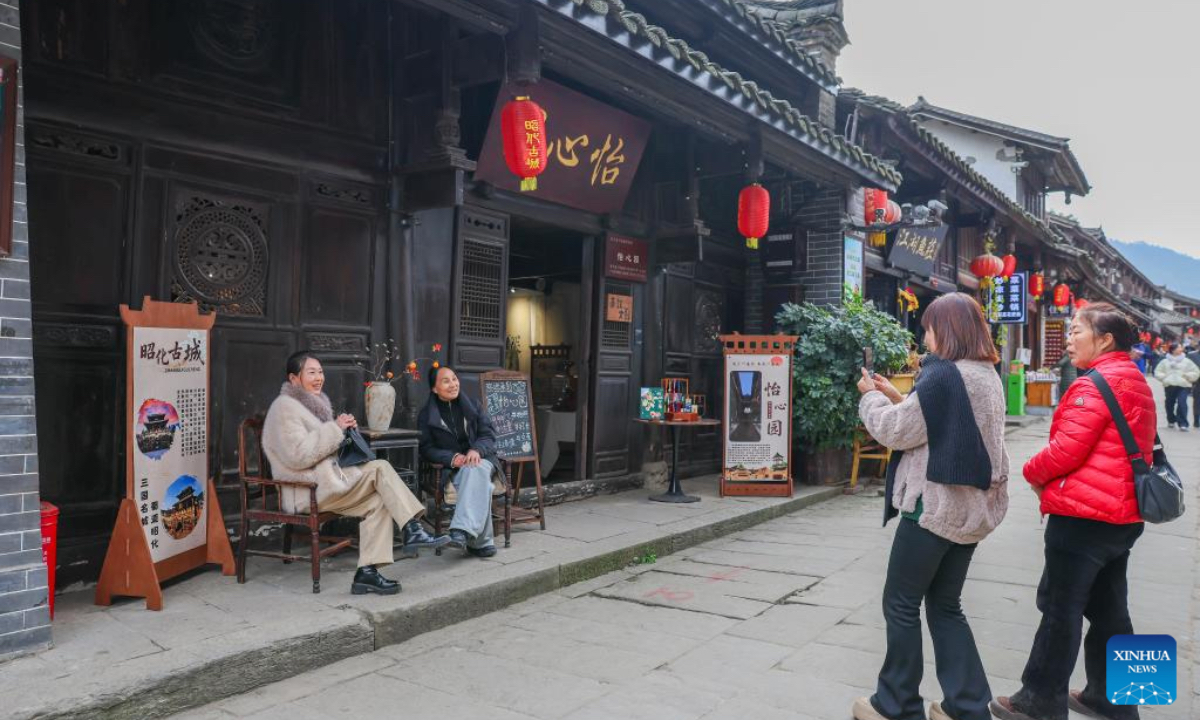 Tourists pose for photos in Zhaohua ancient town in Zhaohua District of Guangyuan City, southwest China's Sichuan Province, Dec. 13, 2025. Zhaohua ancient town, located in Guangyuan City of southwest China's Sichuan Province, sits at the confluence of the Bailong River, the Jialing River, and the Qingjiang River. As a well-preserved ancient town, it carries a history of over 2,300 years. However, due to old infrastructure and unplanned construction, the ancient town once fell into disorder with residents living in the town having to undergo various difficulties. In order to refresh the ancient town, since 2012, Zhaohua District has launched a project to preserve the villages as a whole. While improving the village environment, the preservation project brings along local rural tourism, allowing the ancient town to be revitalized through preservation. (Xinhua/Wu Di)