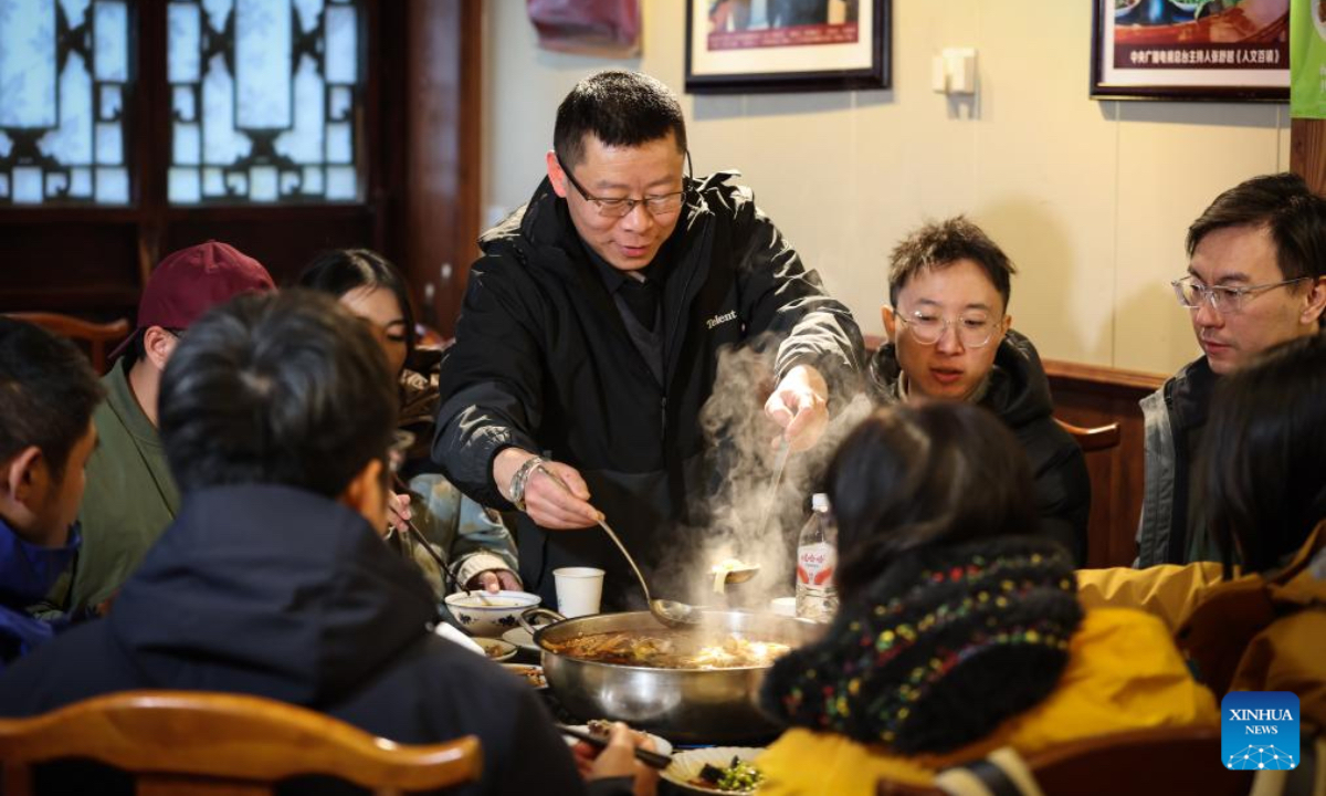Zhai Zhigang, a restaurant owner, serves the guests in his restaurant in Zhaohua ancient town in Zhaohua District of Guangyuan City, southwest China's Sichuan Province, Dec. 13, 2025. Zhaohua ancient town, located in Guangyuan City of southwest China's Sichuan Province, sits at the confluence of the Bailong River, the Jialing River, and the Qingjiang River. As a well-preserved ancient town, it carries a history of over 2,300 years. However, due to old infrastructure and unplanned construction, the ancient town once fell into disorder with residents living in the town having to undergo various difficulties. In order to refresh the ancient town, since 2012, Zhaohua District has launched a project to preserve the villages as a whole. While improving the village environment, the preservation project brings along local rural tourism, allowing the ancient town to be revitalized through preservation. (Xinhua/Pan Yulong)