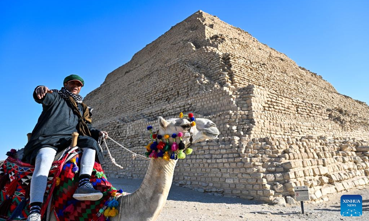 A man rides a camel in front of the Step Pyramid in the Saqqara necropolis, Giza, Egypt, Dec. 18, 2025. (Xinhua/Xin Mengchen)