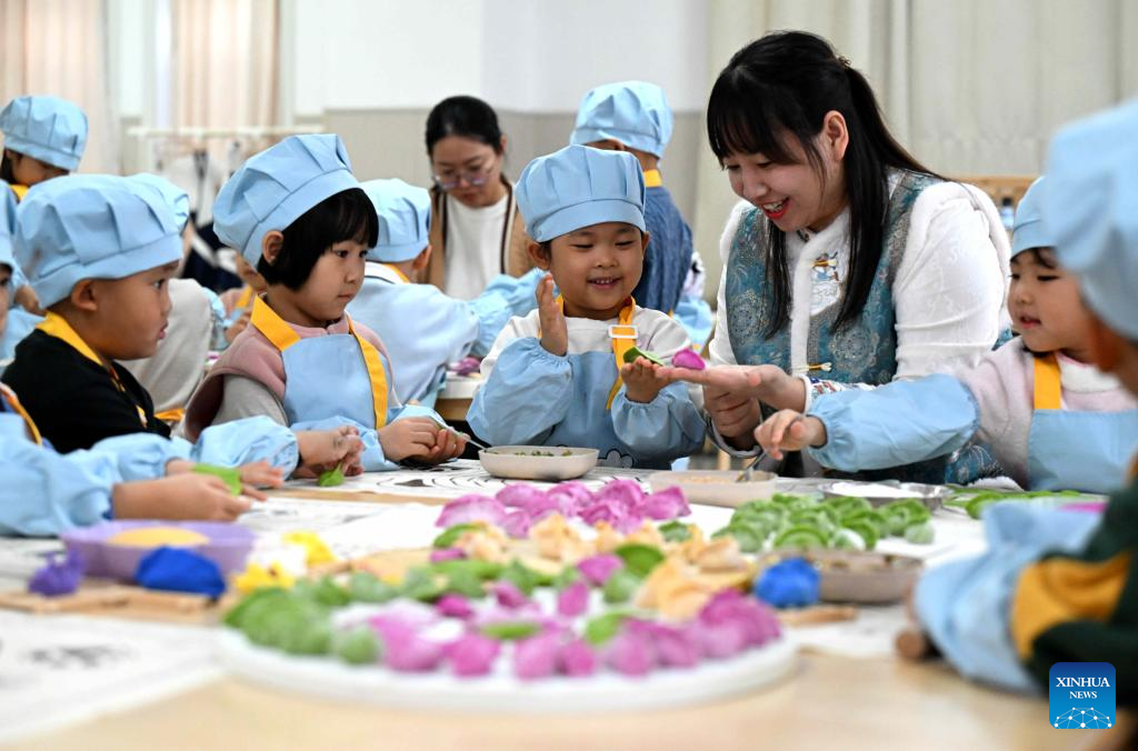 A teacher teaches children to make dumplings at a kindergarten in Zunhua City, north China's Hebei Province, Dec. 19, 2025. Winter Solstice, the shortest day of the year, which will fall on Dec. 21 this year, denotes the beginning of deep winter and a break from farming in traditional agricultural society in Chinese culture. Northern China has maintained the tradition of eating dumplings on this day, while people in southern China eat tangyuan (glutinous rice balls). (Photo by Liu Mancang/Xinhua)