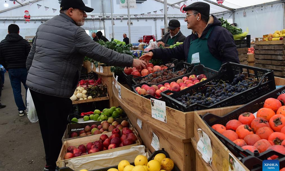 People buy fruits at an agricultural products trade fair in Baku, Azerbaijan, Dec. 21, 2025. With more than 140 specialties from over 80 farms and agricultural product processing enterprises across the country, the trade fair opened here on Saturday, and will run through Dec. 30. (Xinhua/Chen Junfeng)