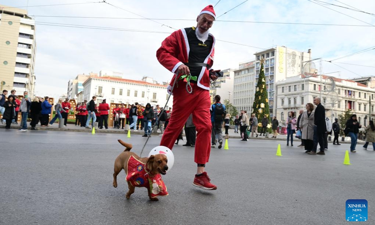 A man and his pet dog participate in the Athens Santa Run 2025 in Athens, Greece, Dec. 21, 2025. Thousands of participants dressed as Santa Claus joined the annual Athens Santa Run, a festive and charitable 2.8-km race. (Xinhua/Marios Lolos)