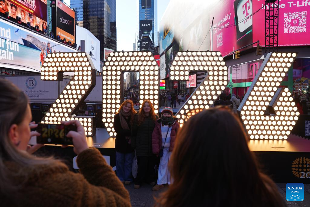 People pose for photos in front of a light installation for the upcoming 2026 at Times Square in New York, the United States, Dec. 22, 2025. (Xinhua/Zhang Fengguo)