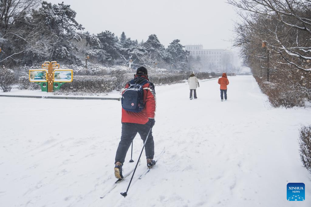 A man wearing a pair of skis is pictured on the street amid snow in Changchun, northeast China's Jilin Province, Dec. 23, 2025. Changchun on Tuesday experienced snowfalls due to the impact of a new cold front. (Xinhua/Xu Chang)