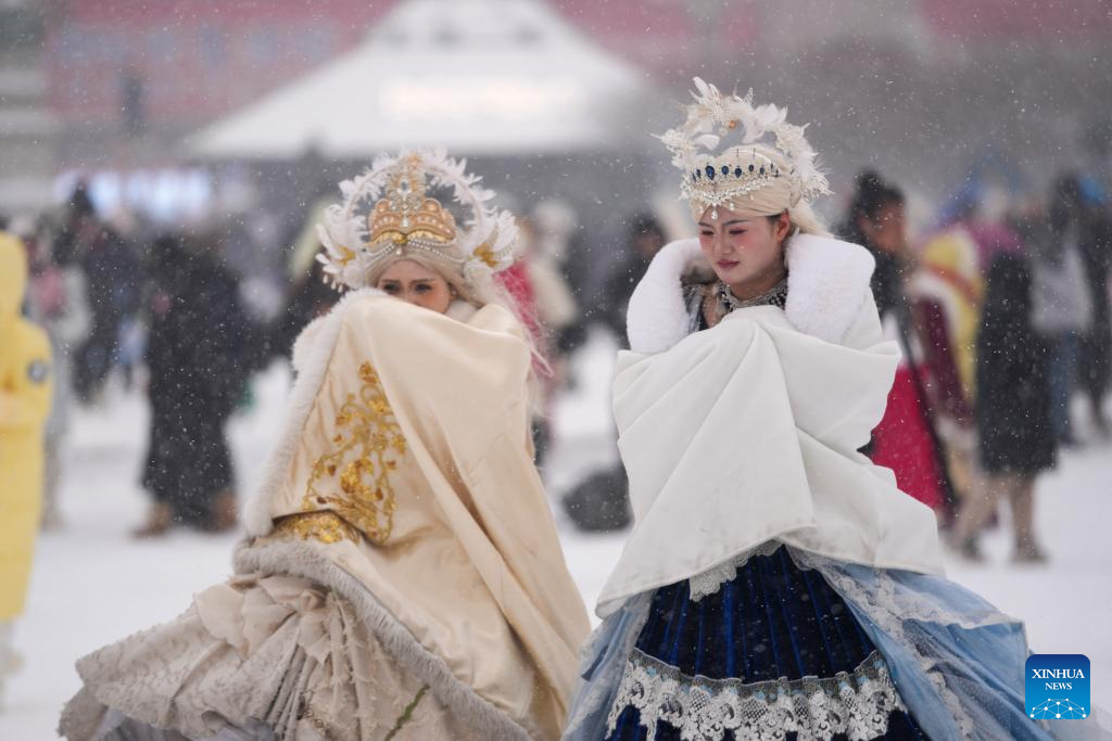 Visitors walk in snow at Harbin Architectural Art Square in Harbin, northeast China's Heilongjiang Province, Dec. 23, 2025. The meteorological observatory of Harbin issued a yellow alert for blizzard on Tuesday. (Xinhua/Wang Jianwei)