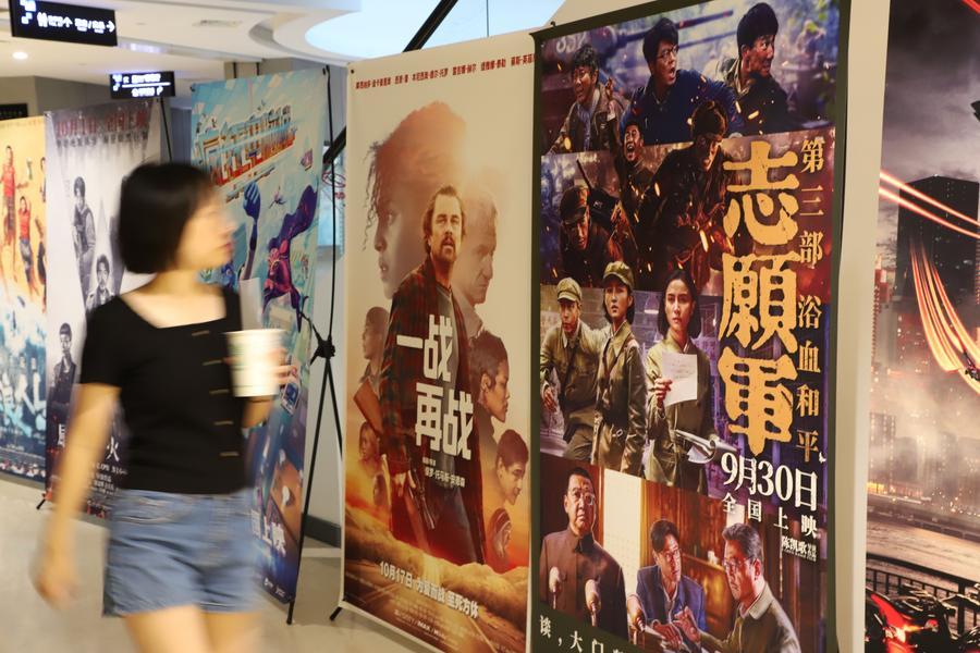 A woman walks past the film posters at a cineplex in Xiamen, southeast China's Fujian Province, Oct. 8, 2025. (Photo by Ze Demeng/Xinhua)