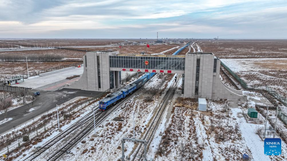 An aerial drone photo taken on Dec. 22, 2025 shows an inbound China-Europe freight train passes through a land port in Erenhot, north China's Inner Mongolia Autonomous Region. Erenhot, the largest land port on the China-Mongolia border, is a pivotal point of the China-Mongolia-Russia Economic Corridor. As of Dec. 22, inbound and outbound passenger traffic volumes and the number of vehicles driving through Erenhot reached 2.753 million and 741,000, respectively, up by 8.8 percent and 12.1 percent compared with the same period of last year. (Xinhua/Ma Jinrui)