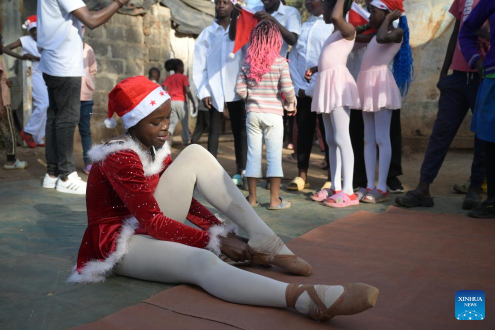 A young dancer puts on her shoes on a simple stage at the Kibera slum in Nairobi, Kenya, Dec. 23, 2025. A Christmas ballet performance organized by the Kibera Ballet School was held here on Tuesday, attracting many local residents to watch. (Xinhua/Yang Guang)