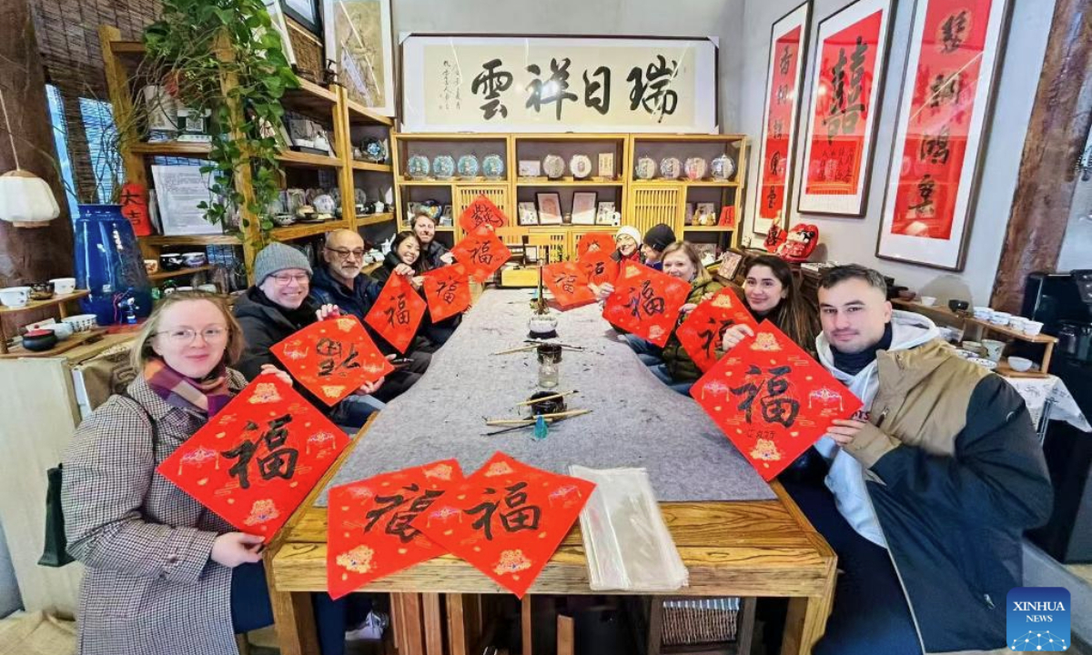 Sun Shuli's team take foreign tourists to experience Chinese calligraphy in Beijing, capital of China, in December 2025. (Xinhua)