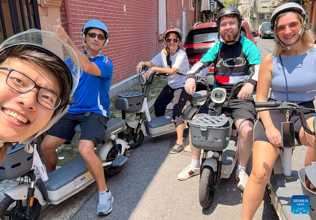 A member of Eastbound and Beyond takes a selfie with foreign tourists in east China's Shanghai in August 2025. (Xinhua)