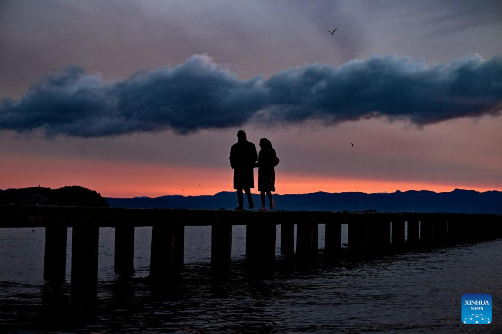 People walk on Ohrid Lake shore at sunset in Ohrid, Republic of North Macedonia, Dec. 24, 2025. (Photo by Tomislav Georgiev/Xinhua)