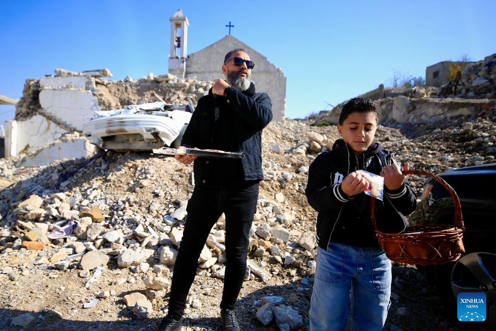 Locals distribute sweets on Christmas in front of a church destroyed by the Israeli army during the war, in southern Lebanese village of Yaroun, Dec. 25, 2025. The church had stood for 102 years. (Photo by Ali Hashisho/Xinhua)