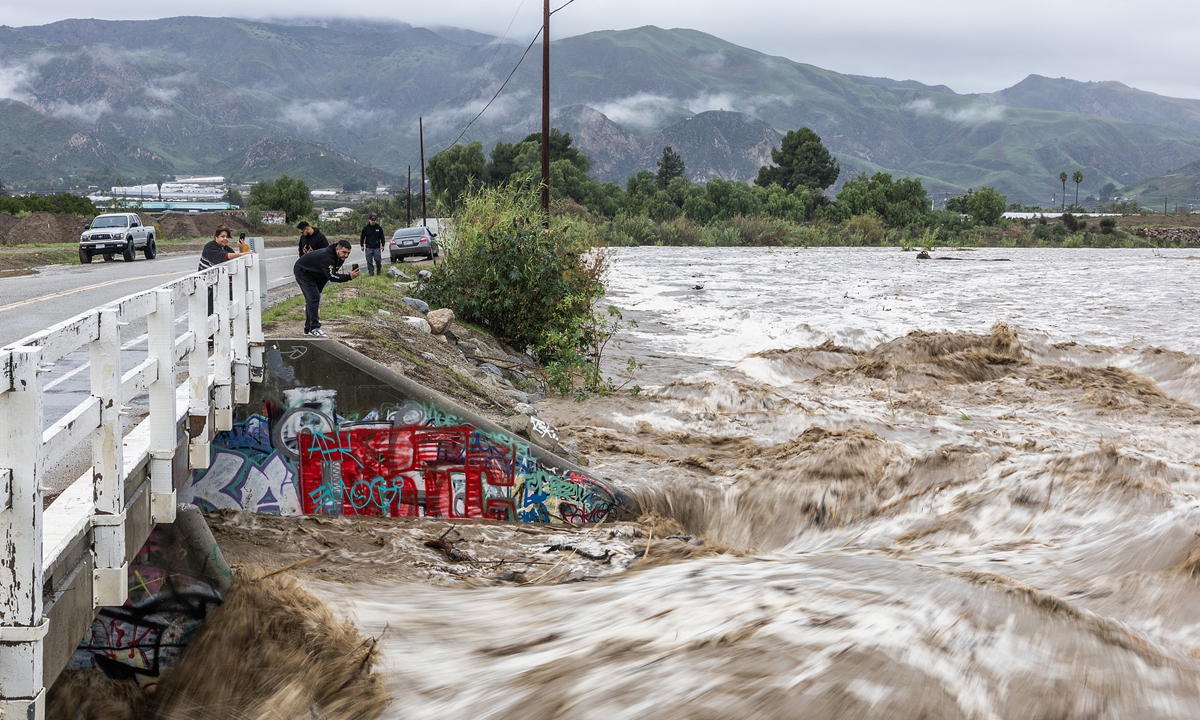 Passersby take pictures of the flowing Santa Clara River on Torrey Road in Fillmore, California on December 24 local time, 2025. CBS reported that powerful a winter storm has swept across California, with heavy rains and gusty winds bringing debris flows that have led to some water rescues and evacuation orders. Photo: VCG