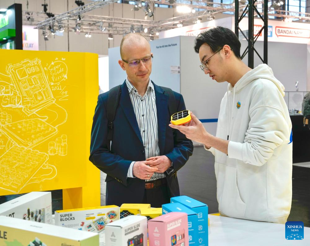 This photo taken in January 2024 shows a staff member (R) introducing a toy produced by Giiker to a client at an international toy fair in Nuremberg, Germany. As traditional toys are stuck in price and homogenization competition, a batch of smart educational toys is quietly opening up new markets at home and abroad. (Xinhua)