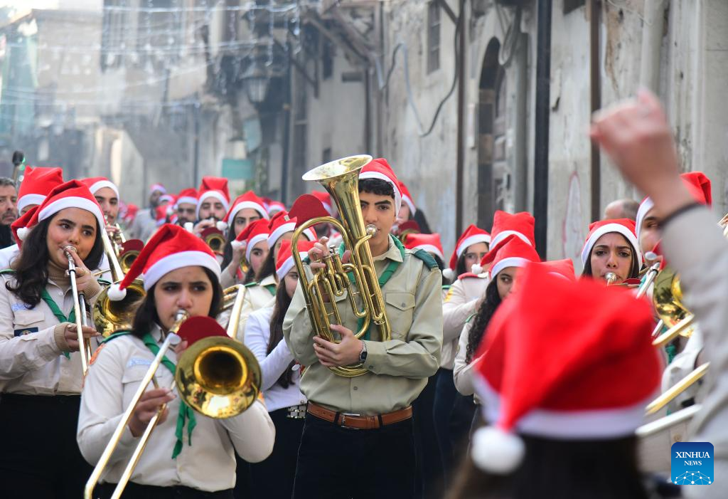 Members of a local scout band wearing Santa hats march through a historic street during a Christmas parade, in Damascus, Syria, Dec. 25, 2025. (Photo by Ammar Safarjalani/Xinhua)