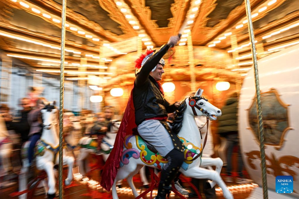 A tourist dressed as a Roman warrior takes a ride in a carousel at Piazza Navona in Rome, Italy, Dec. 27, 2025. (Xinhua/Li Jing)