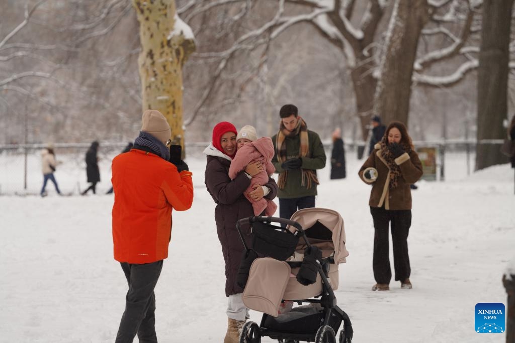 People pose for a photo amid snow at the Central Park in New York, the United States, on Dec. 27, 2025. (Xinhua/Zhang Fengguo)