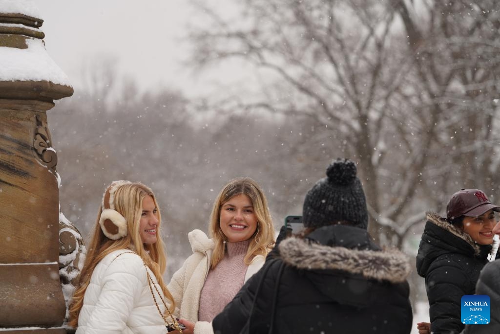 People pose for a photo amid snow at the Central Park in New York, the United States, on Dec. 27, 2025. (Xinhua/Zhang Fengguo)