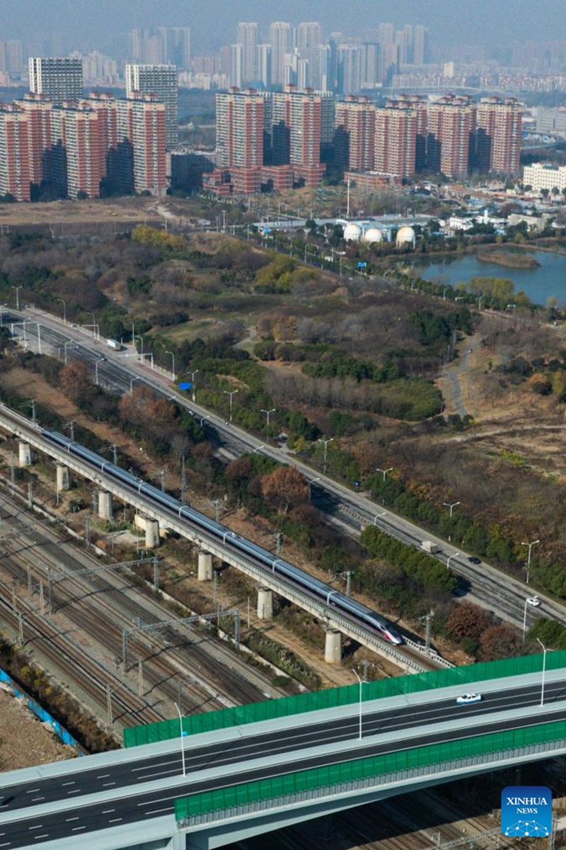 An aerial drone photo shows a bullet train running under the northern section of Gutian First Road in Wuhan, central China's Hubei Province, Dec. 28, 2025. The northern section of Gutian First Road in Wuhan was officially completed and opened to traffic on Sunday. The 2.78-kilometer road, crossing the Shanghai-Chongqing-Chengdu high-speed railway, Wuhan-Danjiangkou Railway, and Wuhan Third Ring Road, will benefit residents along the route. (Xinhua/Wu Zhizun)