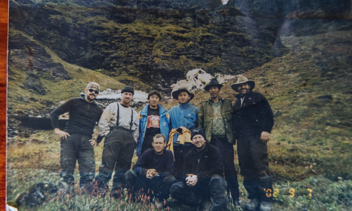 Sonam (second from the right, back row) and members of the China-US joint expedition team pose in a mountainous area with the wreckage of a US transport aircraft from World War II in the background, in Langgong village, Nyingchi, Southwest China's Xizang Autonomous Region, in September 2002. Photo: Courtesy of Sonam