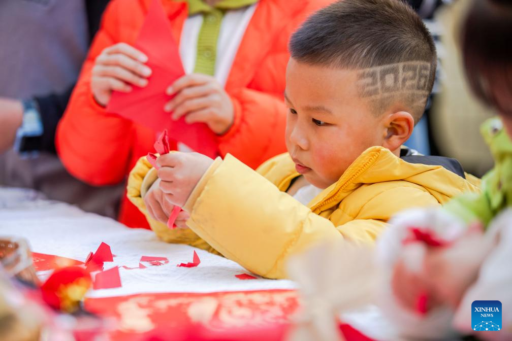 A children makes a paper-cut window decoration in a community in Wenzhou City, east China's Zhejiang Province, Dec. 28, 2025. Various activities are held across China to celebrate the upcoming new year. (Photo by Liu Jili/Xinhua)