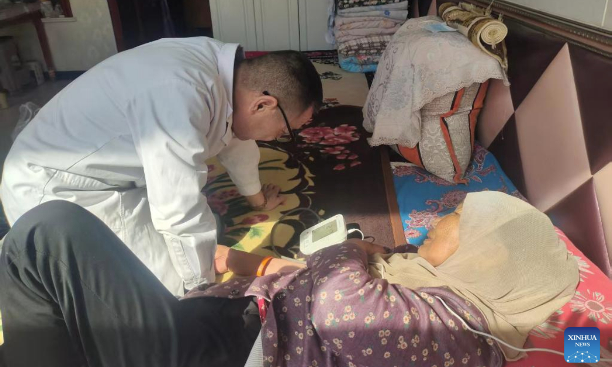 This undated photo shows Ma Junling (L), a doctor from the health center of Hexi Township, measuring blood pressure for Yang Meilan, in Tongxin County, northwest China's Ningxia Hui Autonomous Region. (Xinhua)