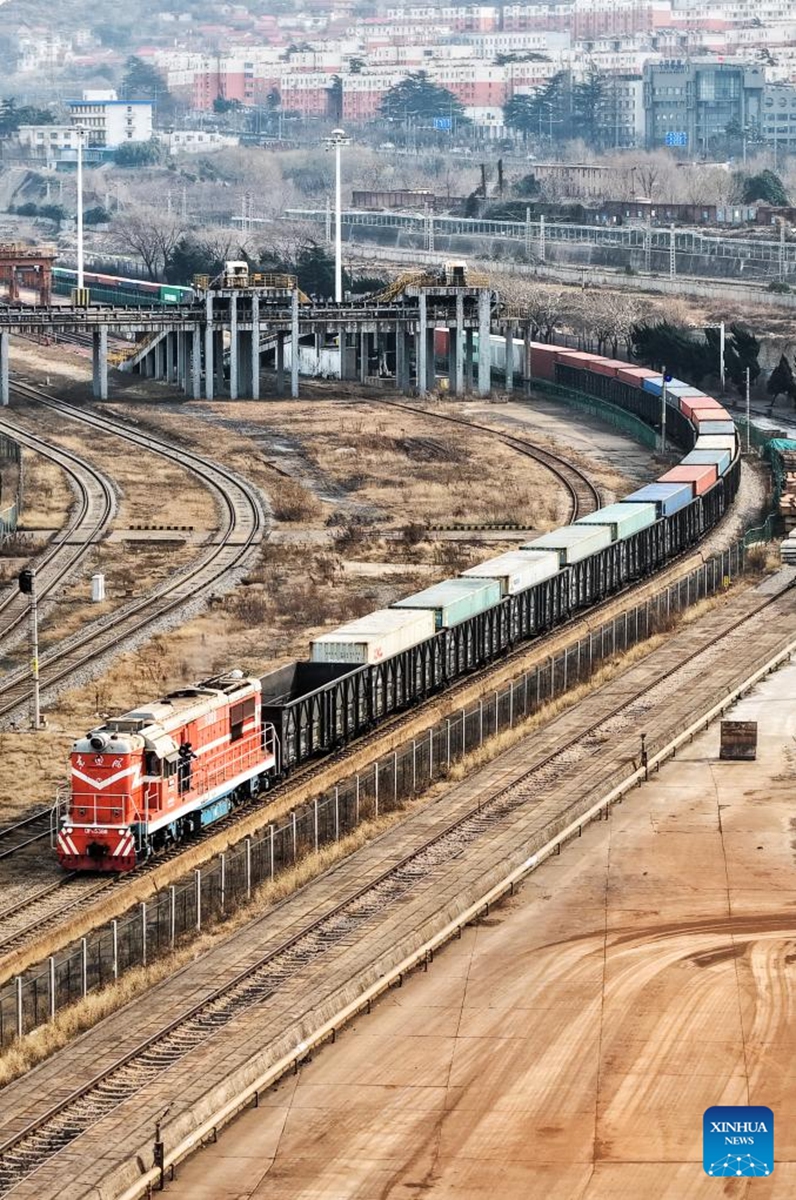 A drone photo taken on Jan. 1, 2026 shows a freight train loaded with auto parts pulling out of the China-Kazakhstan (Lianyungang) Logistics Cooperation Base for Kazakhstan in Lianyungang, east China's Jiangsu Province. It marks the first China-Europe freight train launched by the base in 2026. (Photo by Wang Jianmin/Xinhua)