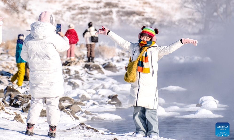 A tourist poses for a photo by the Halha River in the city of Arxan of Hinggan League, north China's Inner Mongolia Autonomous Region, Jan. 1, 2026. Despite Arxan's frigid winter cold, this geothermally-affected section of the Halha River never freezes, which attracts great amount of tourists in winter. (Xinhua/Ma Jinrui)