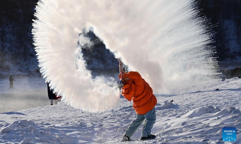 A tourist plays a water to ice game by splashing water into the cold air by the Halha River in the city of Arxan of Hinggan League, north China's Inner Mongolia Autonomous Region, Jan. 1, 2026. Despite Arxan's frigid winter cold, this geothermally-affected section of the Halha River never freezes, which attracts great amount of tourists in winter. (Photo by Wang Zheng/Xinhua)