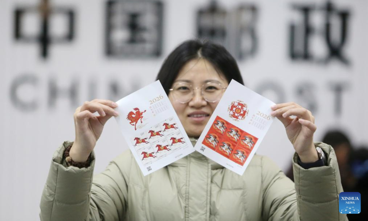 A woman shows special stamps marking the Year of the Horse in Yangzhou, east China's Jiangsu Province, Jan. 5, 2026. China Post on Monday unveiled a set of two special stamps to celebrate the upcoming Chinese zodiac Year of the Horse. (Photo by Meng Delong/Xinhua)