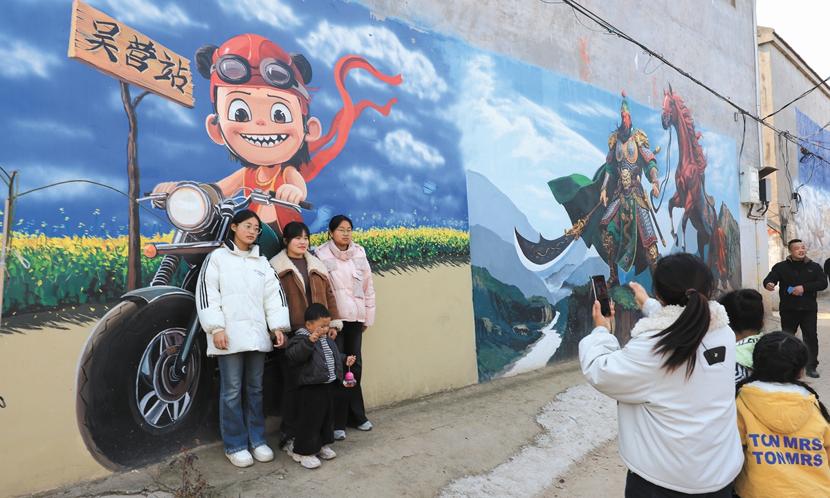 Tourists pose for photos in front of the recently popular wall murals in Wuying village, Shangqiu, Central China's Henan Province, featuring images such as Tiananmen and Nezha, on December 26, 2025. Photo:VCG